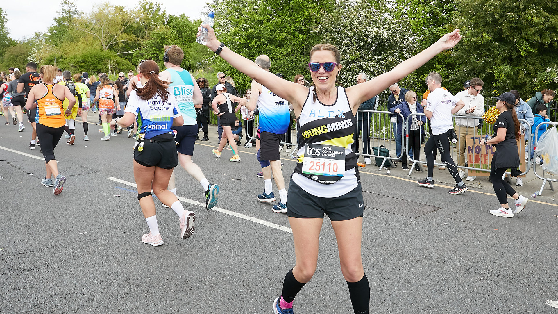 A YoungMinds marathon runner running with their hands in the air and smiling.