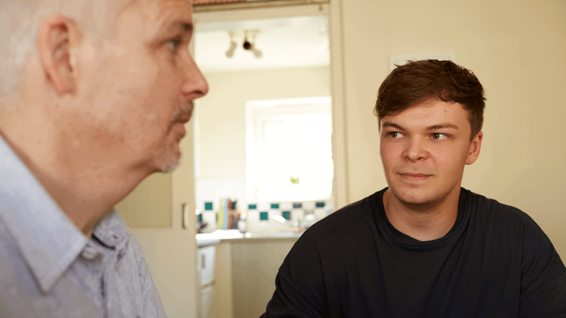 A father and son at home together having a conversation