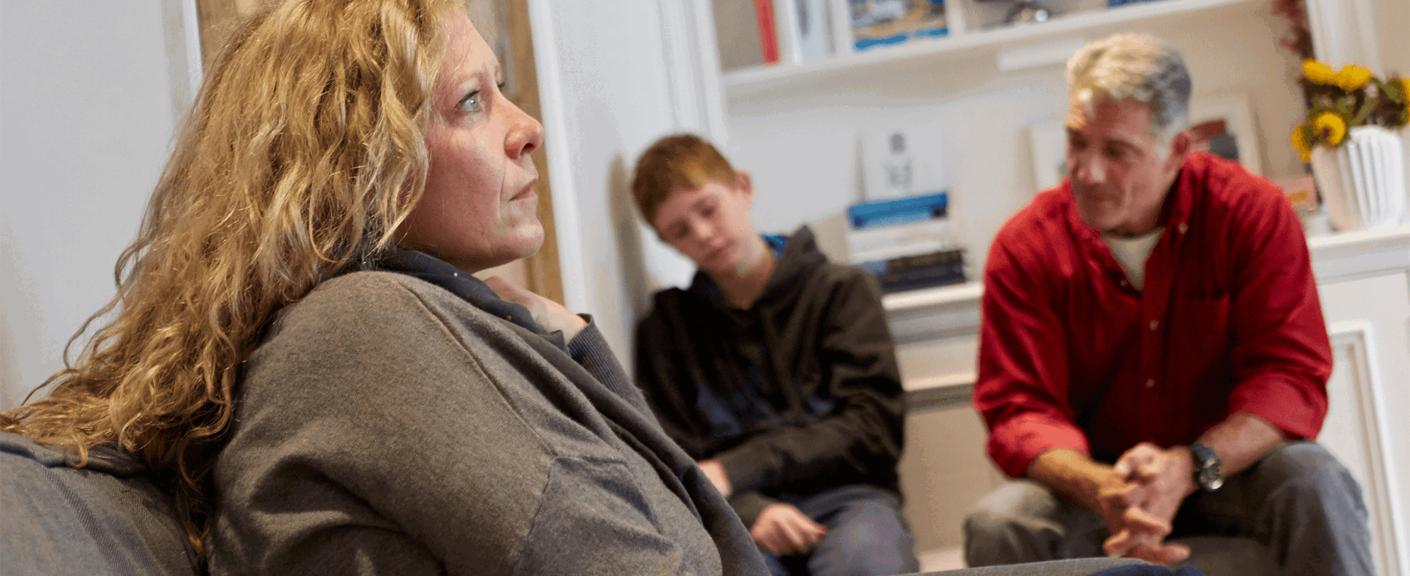 A family sitting in a room looking serious and sad