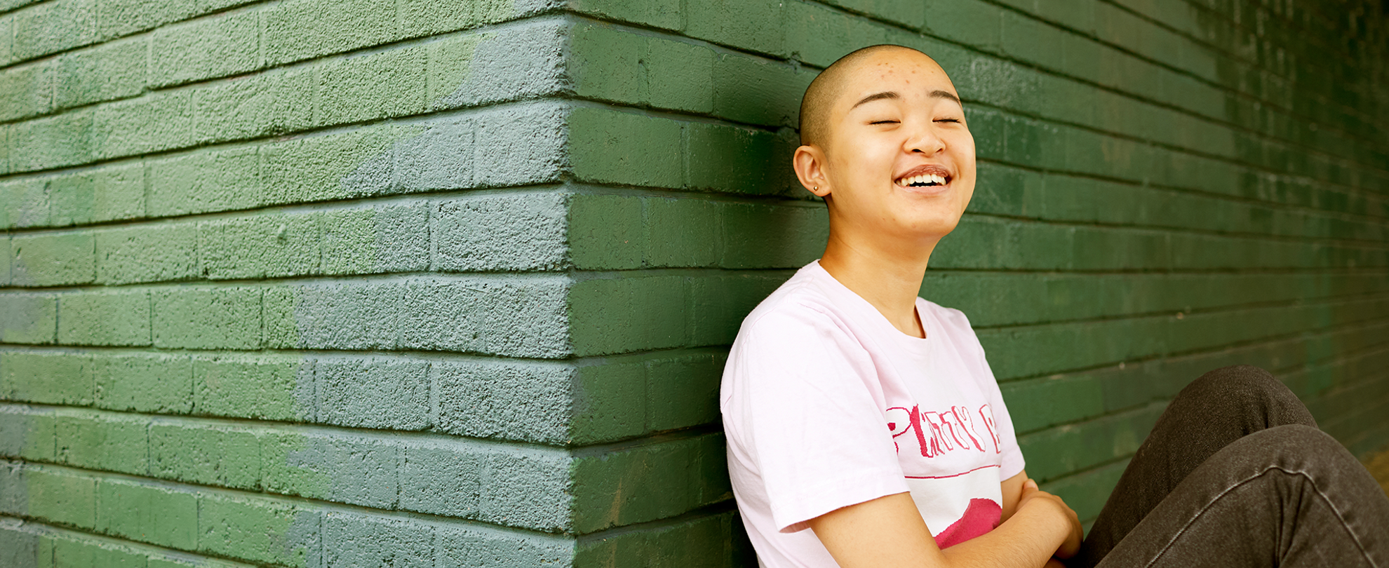 A person leaning against a wall and laughing.