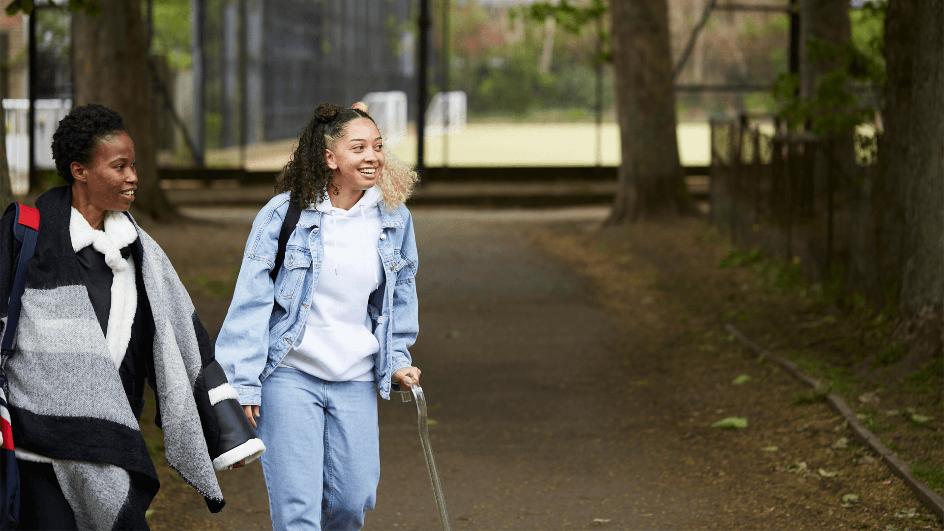 Two young people walking down a park path together.