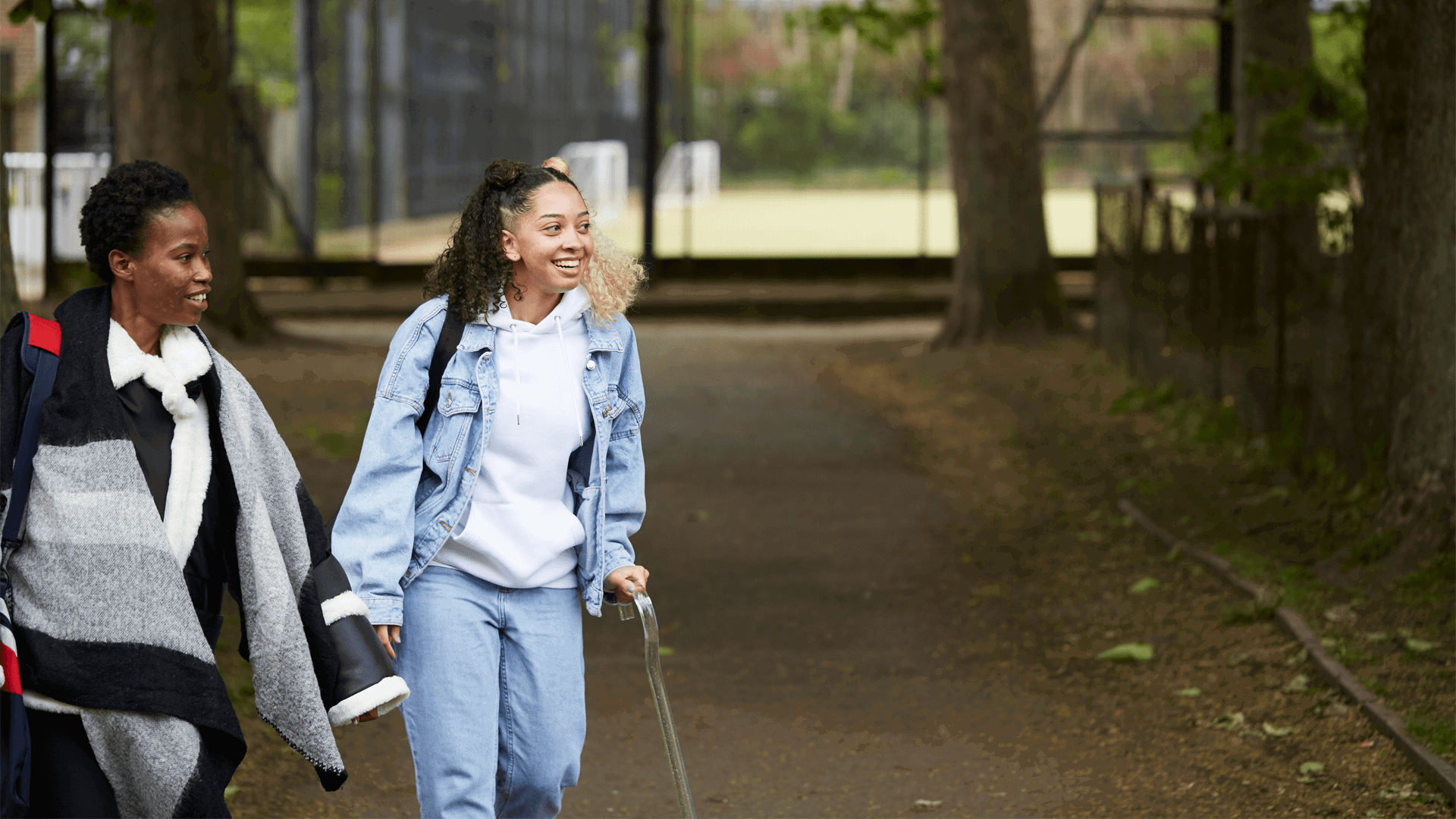 Two young people walking down a park path together.