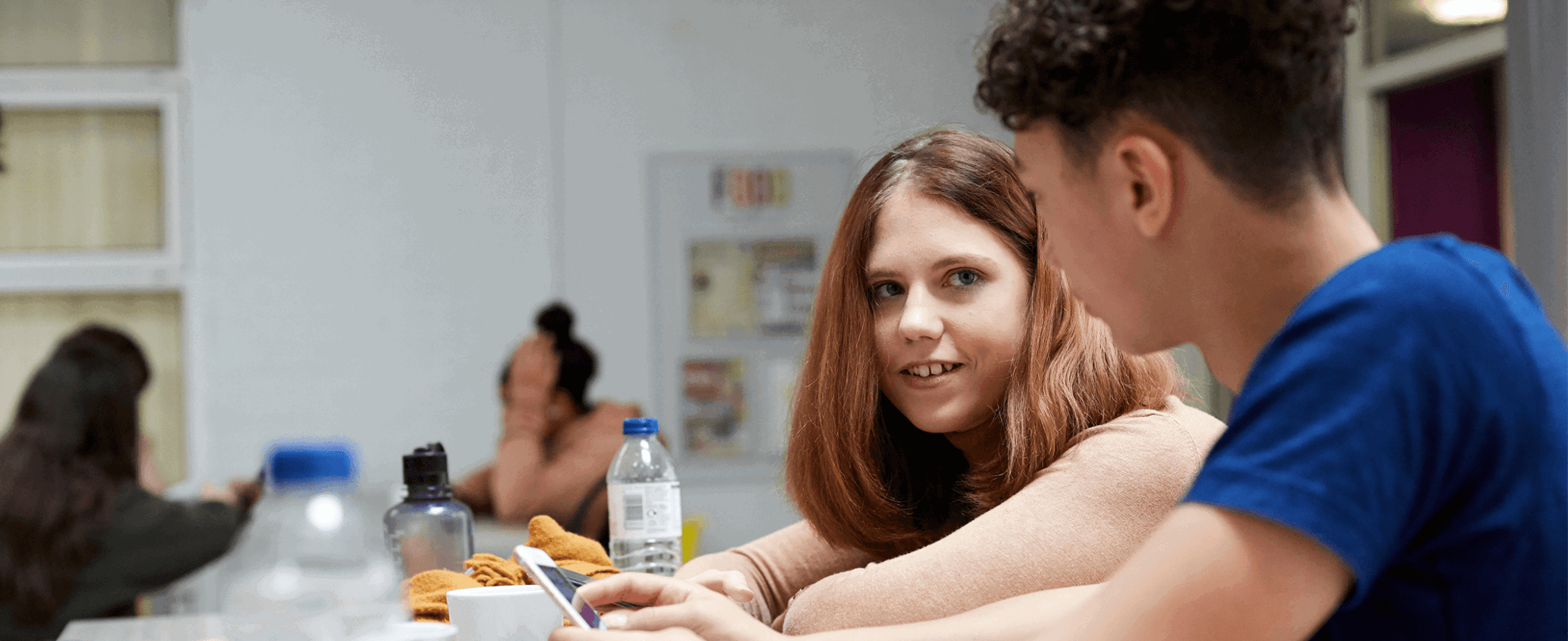 A group of young people sitting together and talking in a school canteen.