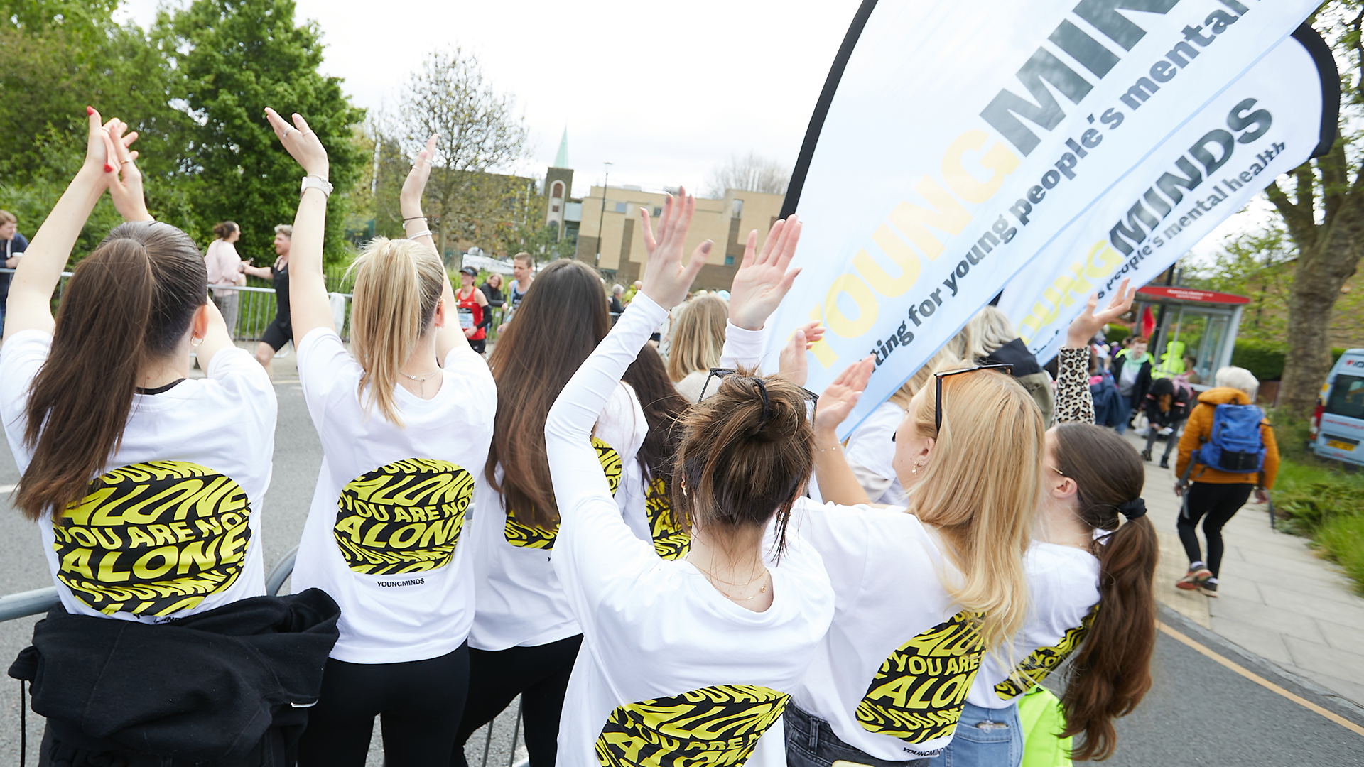 YoungMinds staff cheering marathon runners on from the side line in YoungMinds t-shirts and with YoungMinds banners.