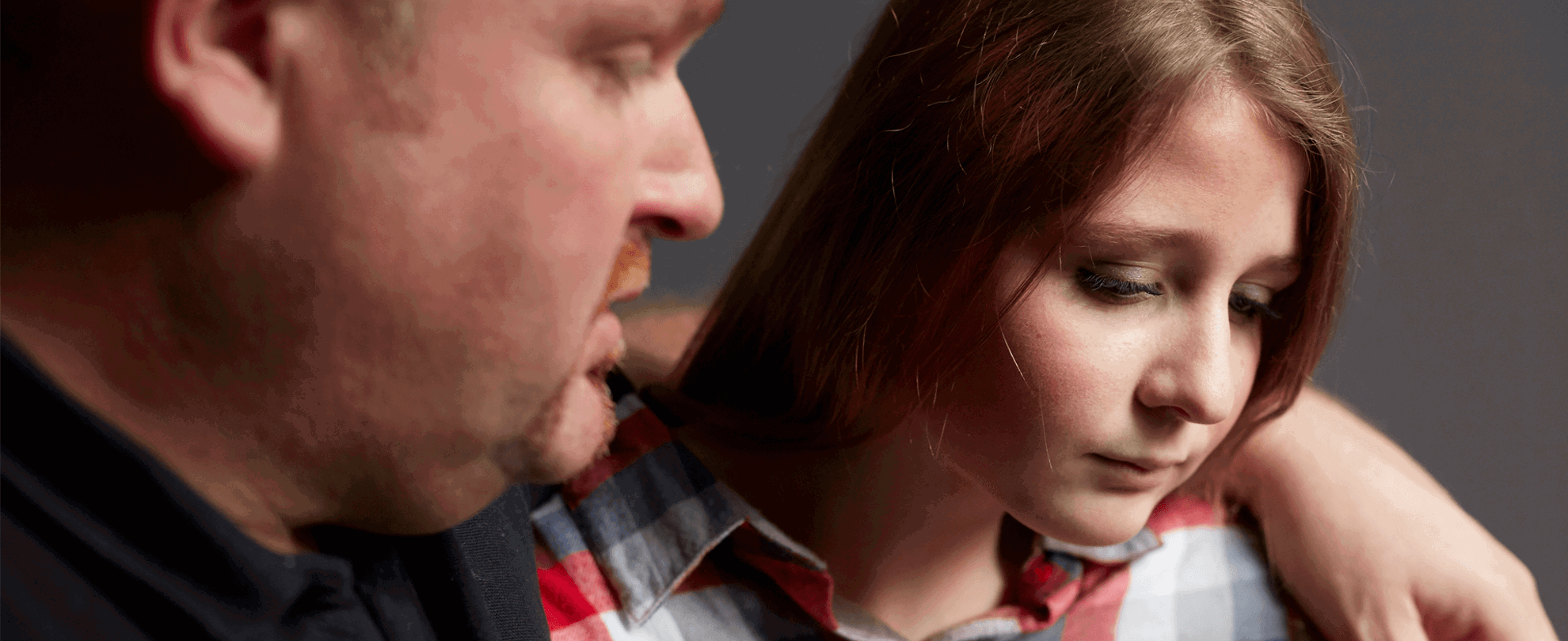 A father comforting his sad daughter with his arm around her