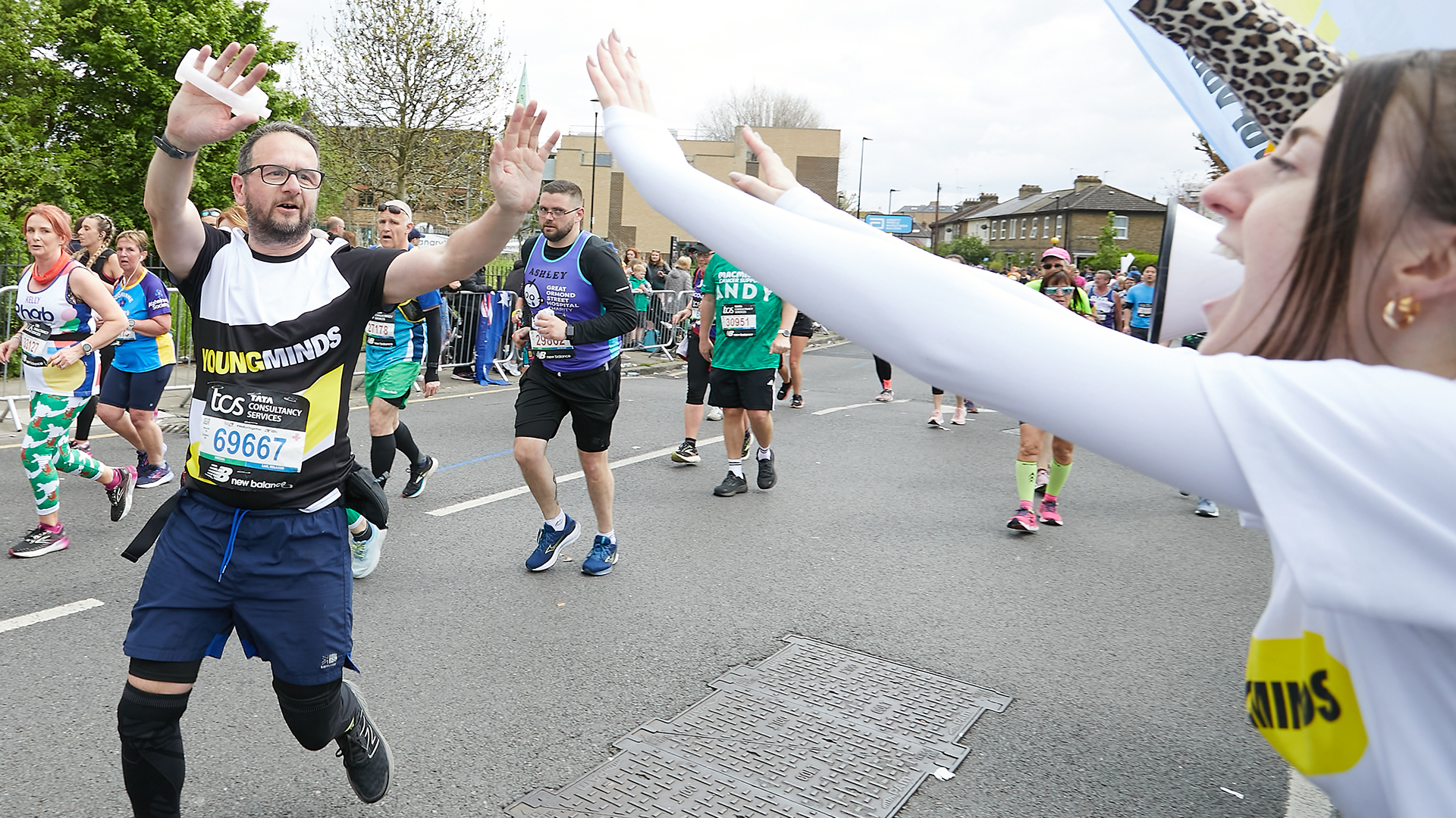 A YoungMinds marathon runner being supported by YoungMinds staff on the side line.