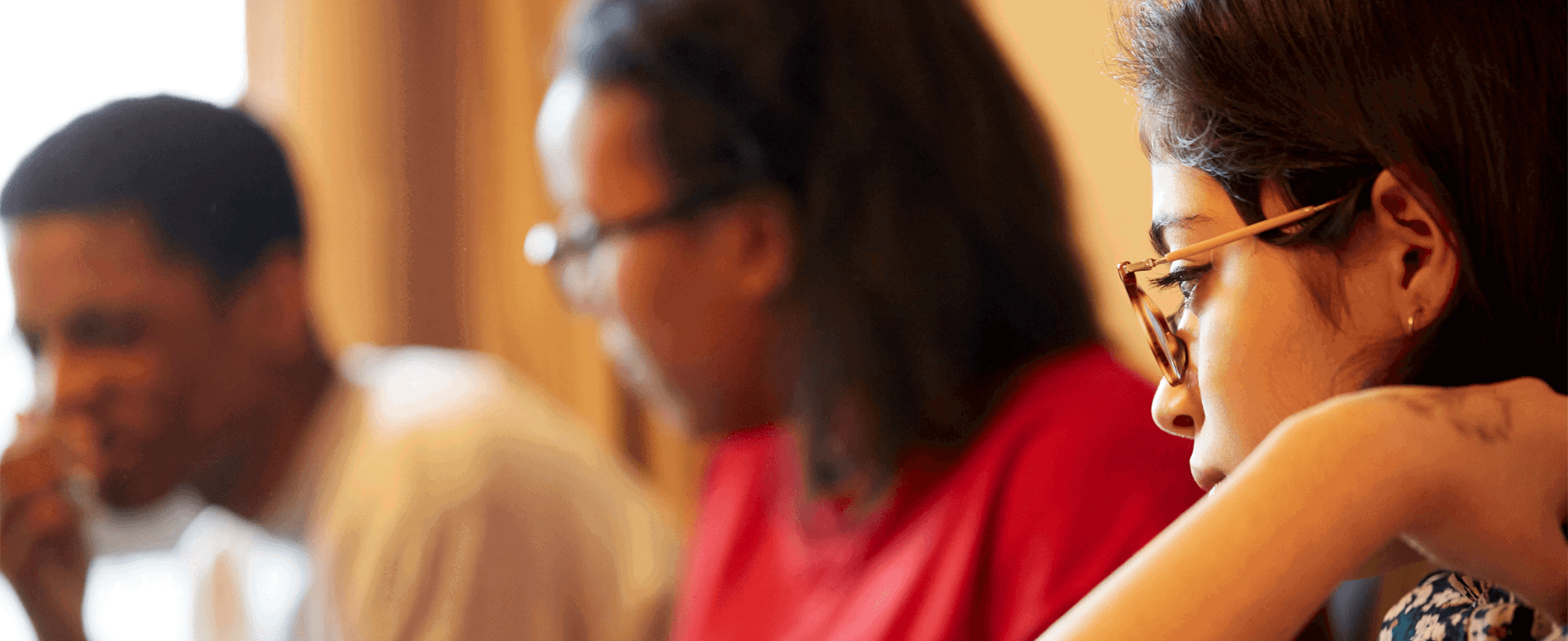 Three young people sitting and talking together in a livingroom.