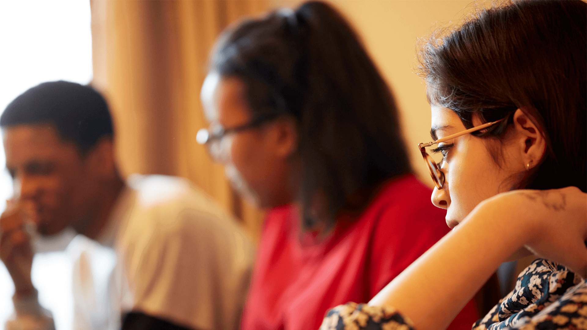 Three young people sitting and talking together in a livingroom.
