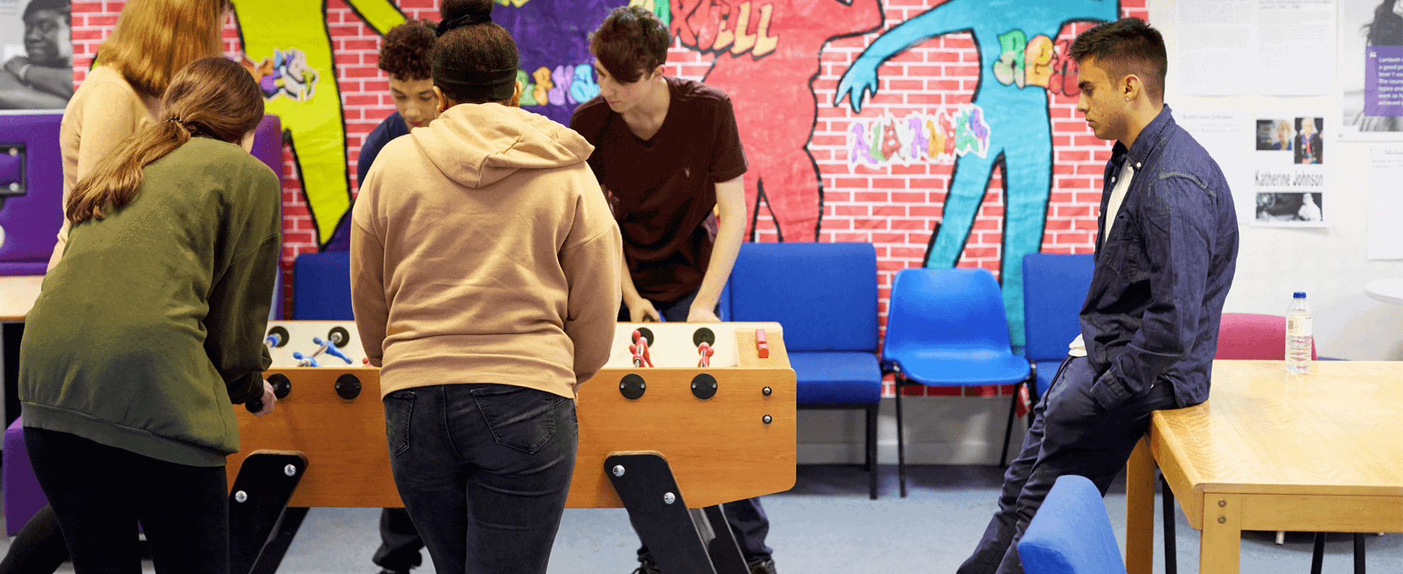 Six young people playing table football in a youth club.