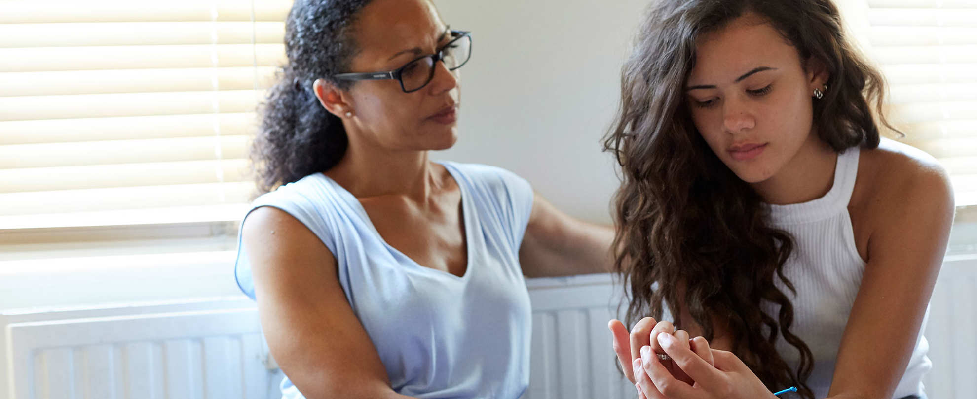 A mother and daughter having a serious discussion at home in front of a radiator