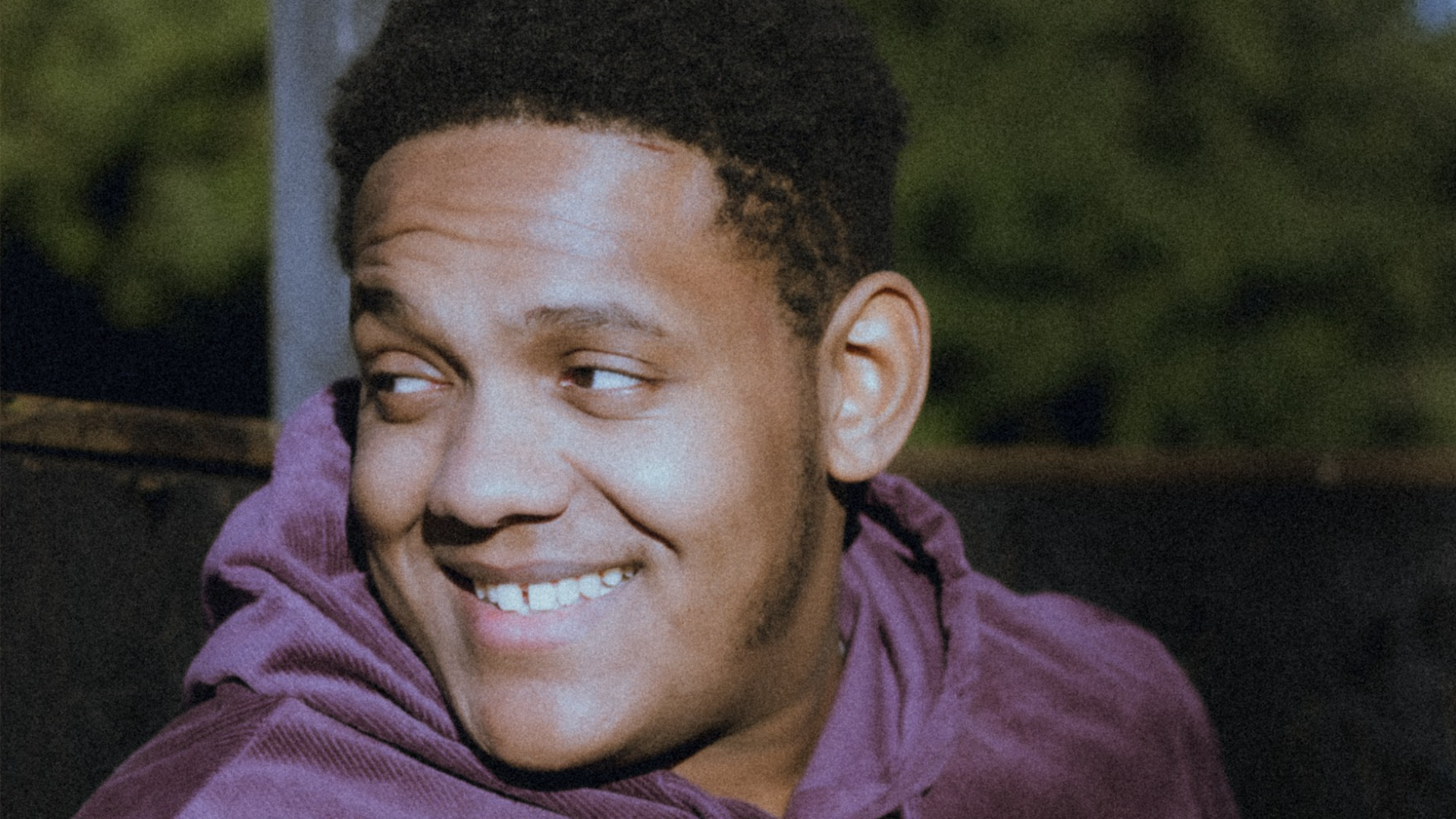 A picture of Josiah smiling, wearing a purple hoody.