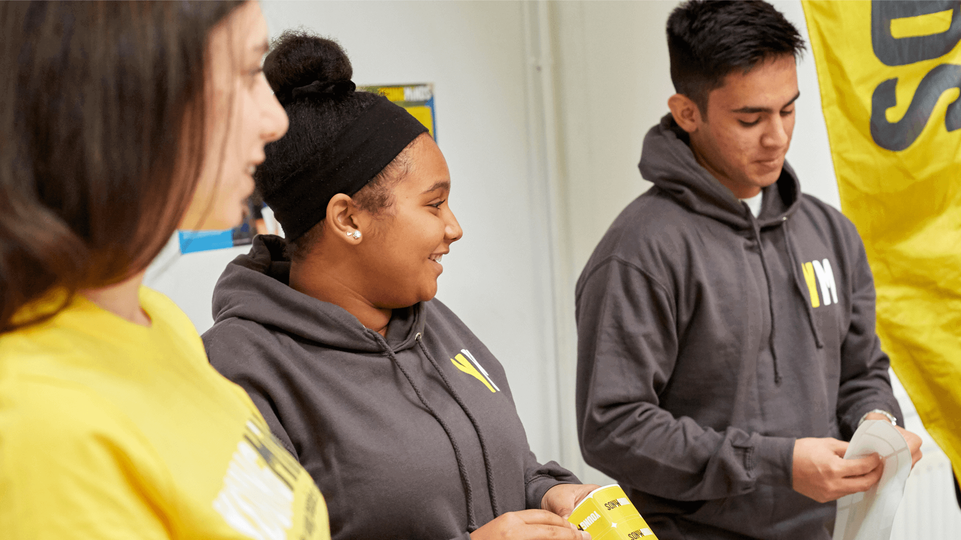 three young people fundraising volunteers wearing YoungMinds hoodie smiling