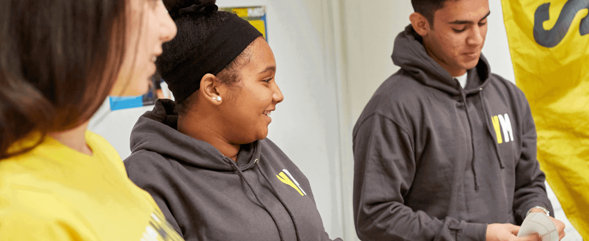 three young people fundraising volunteers wearing YoungMinds hoodie smiling
