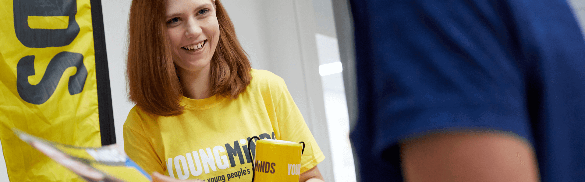 a YoungMinds volunteer wearing yellow YoungMinds shirt smiling in a fundraising event