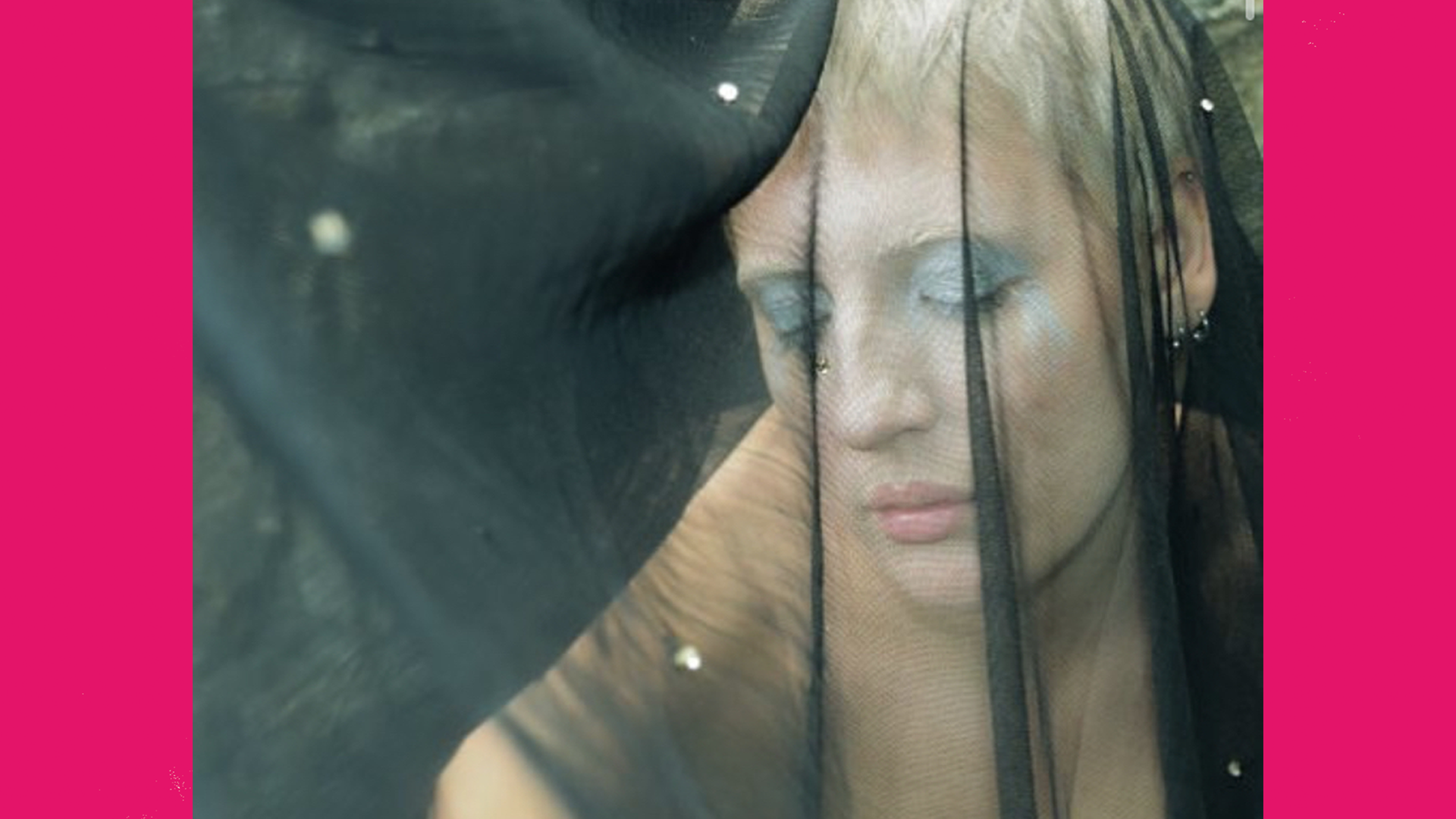 An image of a person in a black veil wearing blue eye makeup.