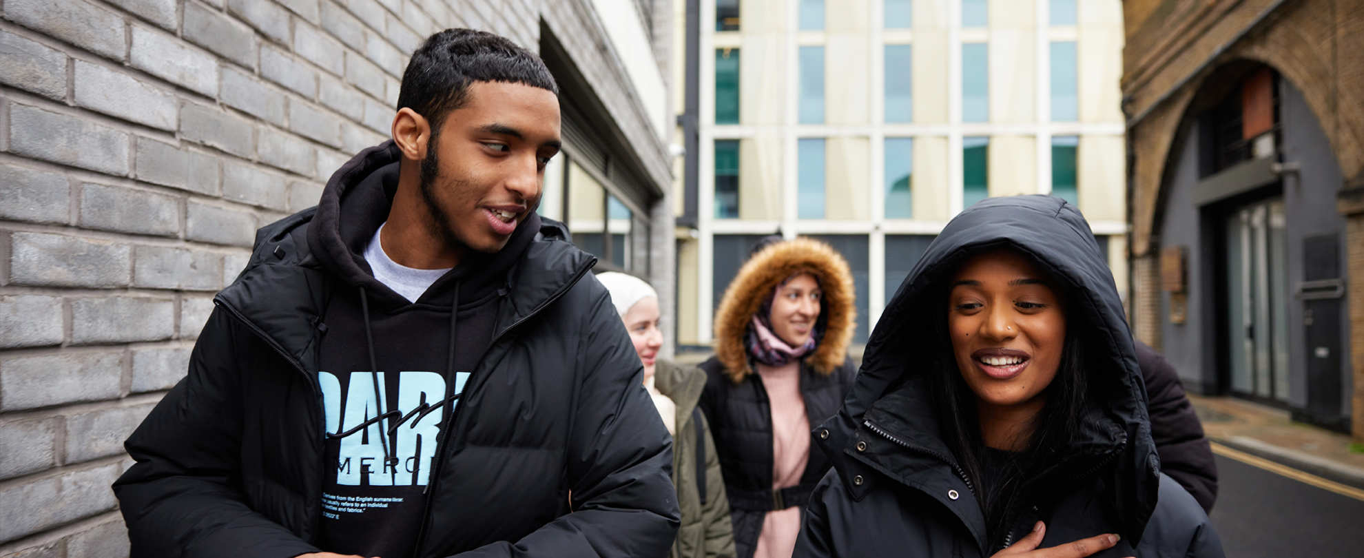 A group of young people walking on the street and talking.