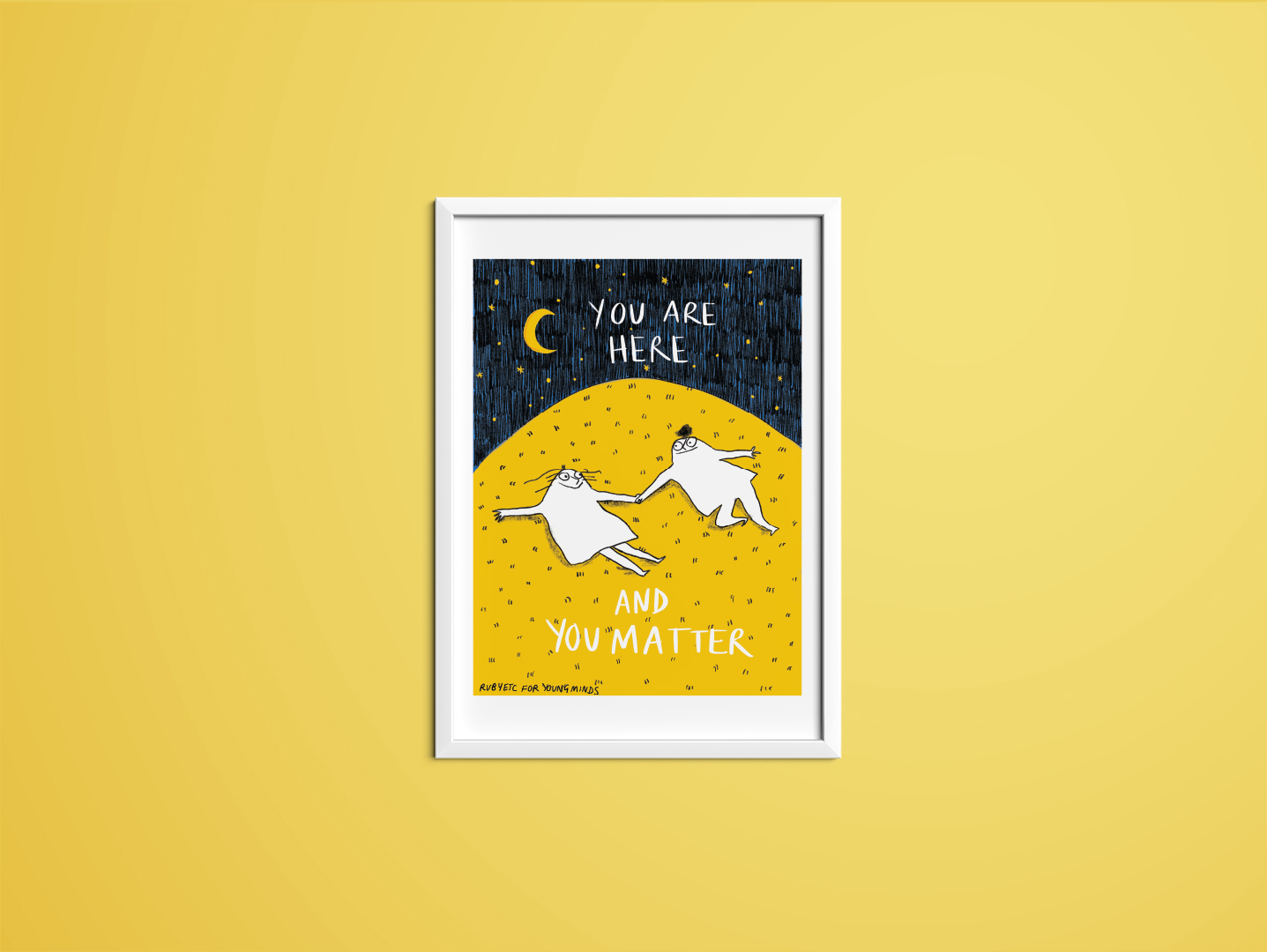 A print by Rubyetc in a white frame with a yellow wall. The print has a night sky at the top with a crescent moon and stars. In the night sky the text reads: you are here. Underneath is a big yellow hill with two people lying on top of the grass. The people are looking at each other and smiling. Underneath the people the text reads: and you matter. In the bottom right hand corner it reads: Rubyetc for YoungMinds.