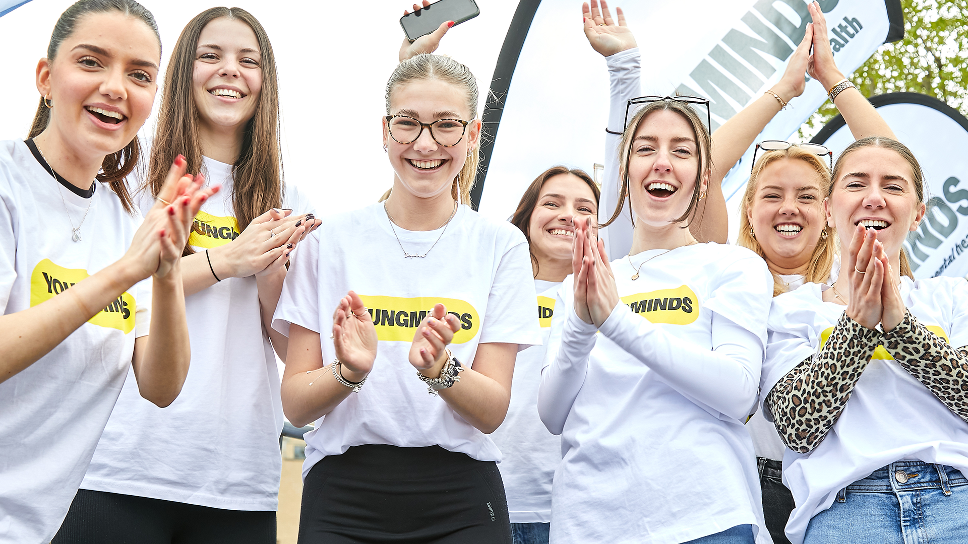 YoungMinds staff cheering marathon runners on from the side line in YoungMinds t-shirts and with YoungMinds banners.
