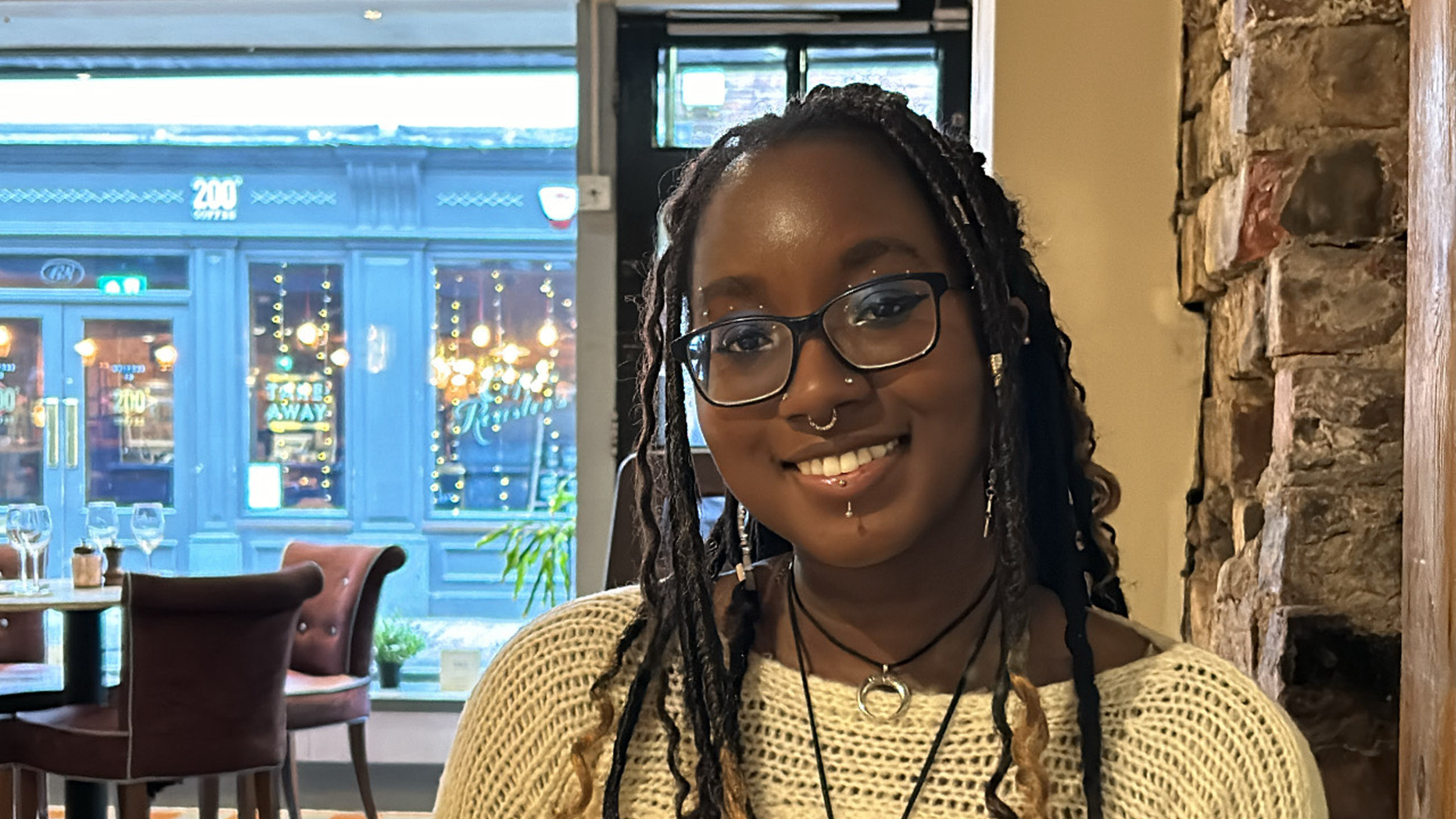 A picture of Charis sitting in a restaurant smiling at the camera.