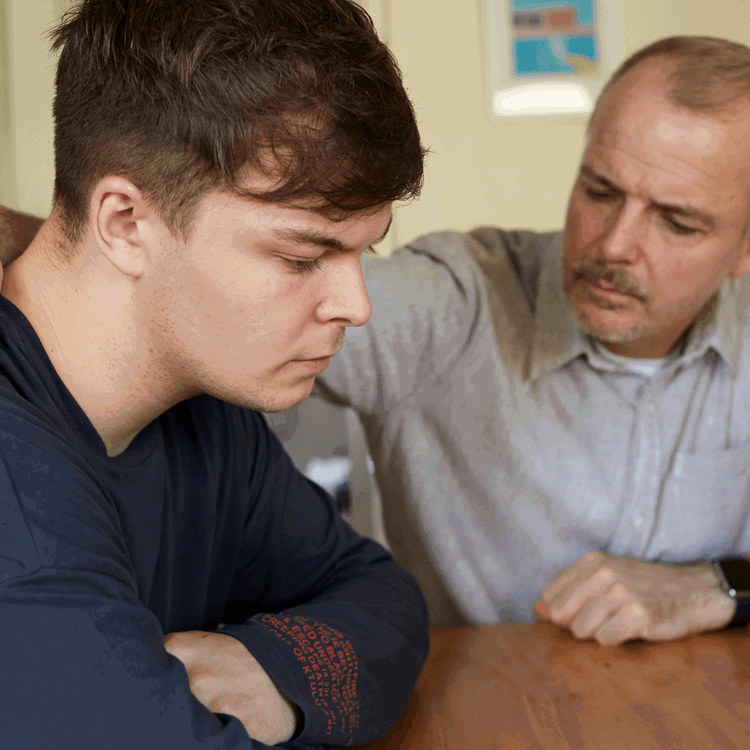 A father comforts his son at the table