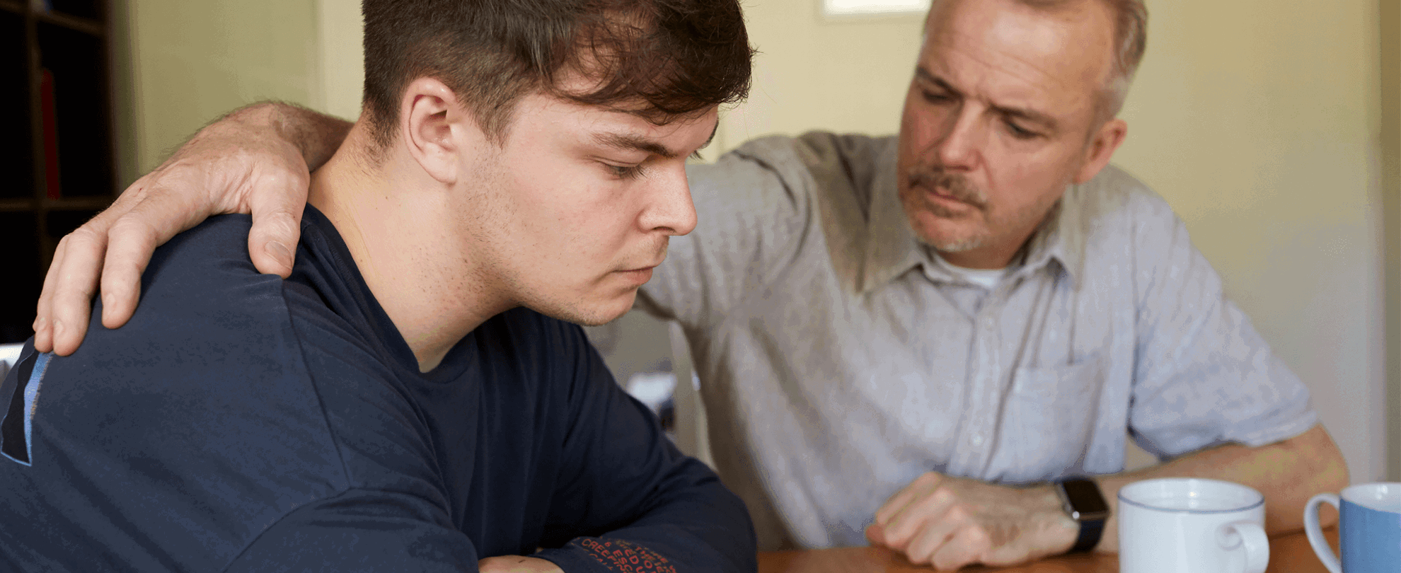 A father comforts his son at the table