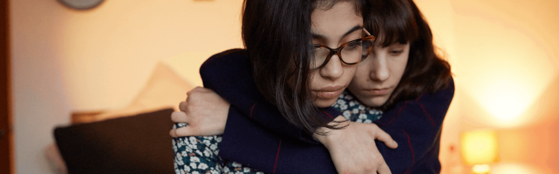 A young person hugging their friend to show support.