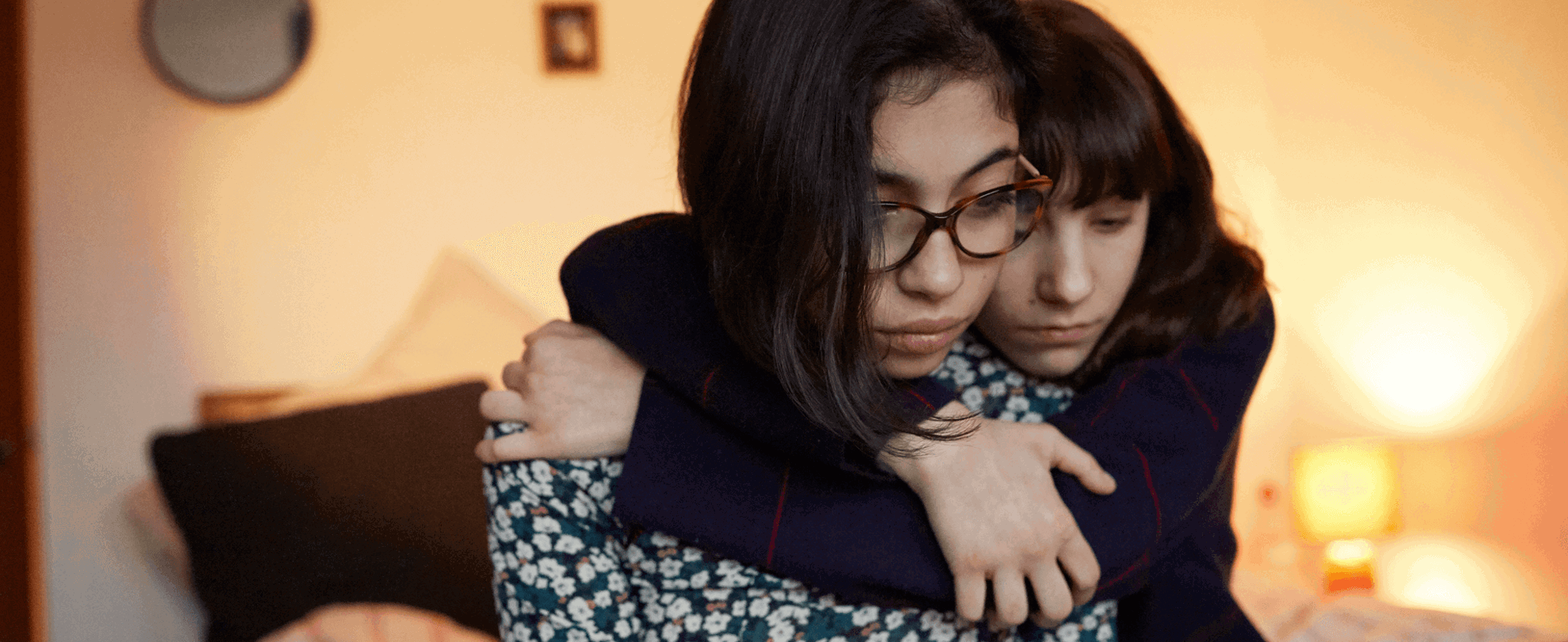 A young person hugging their friend to show support.