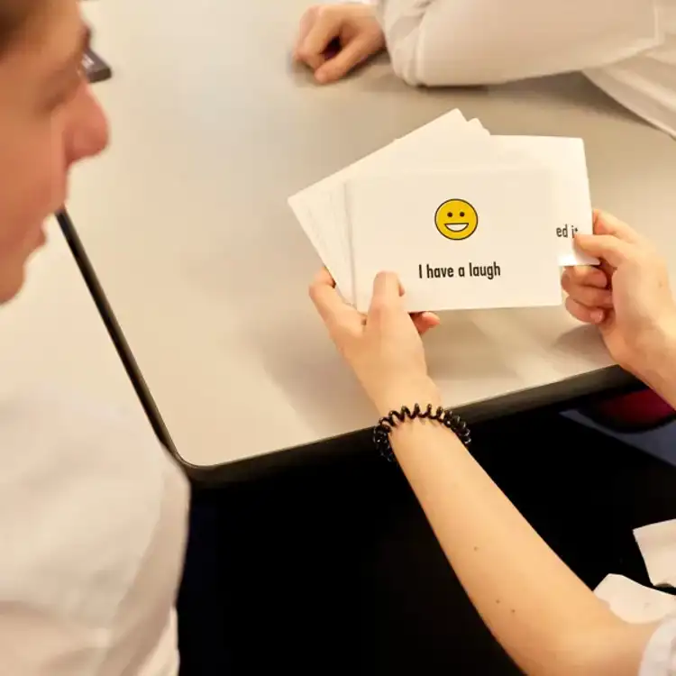 A close up of hands holding YoungMinds secondary resilience cards secondary pack in the classroom.