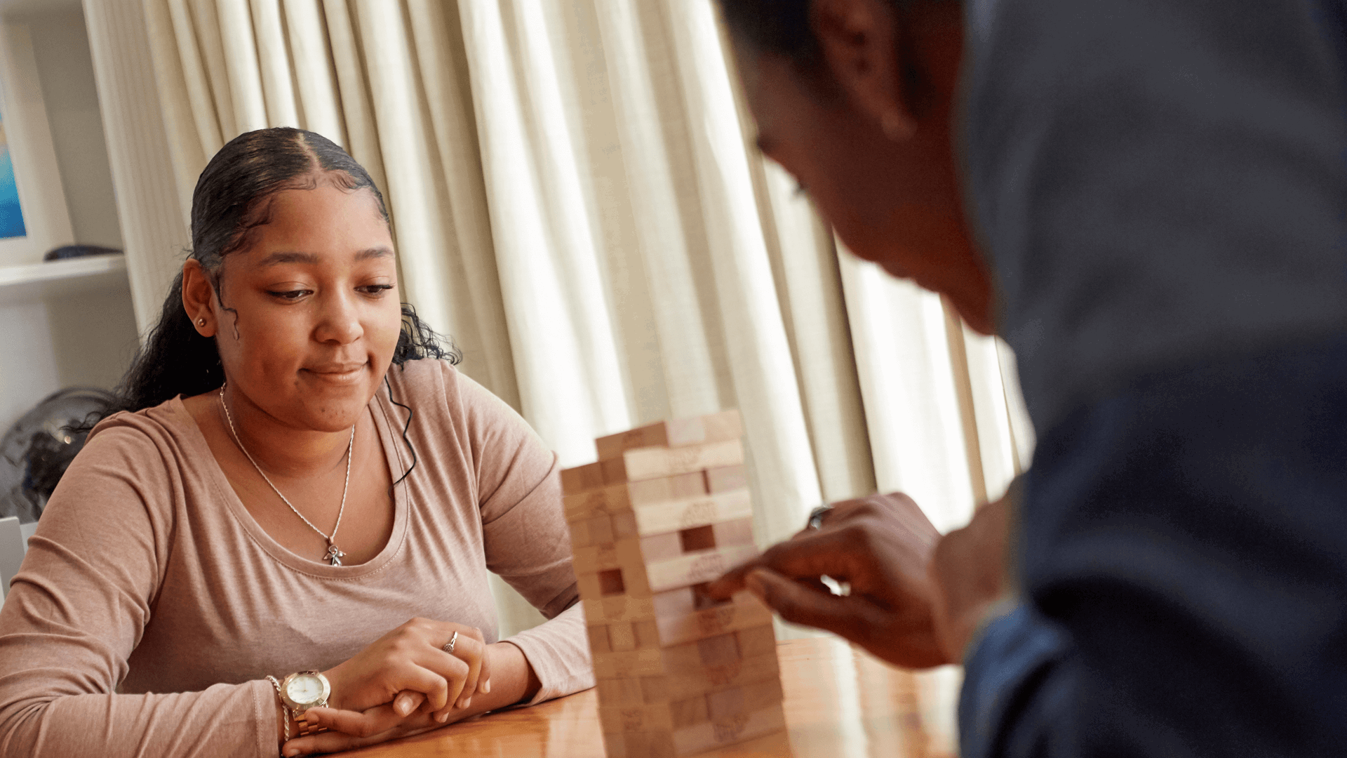 Two people playing jenga at a table