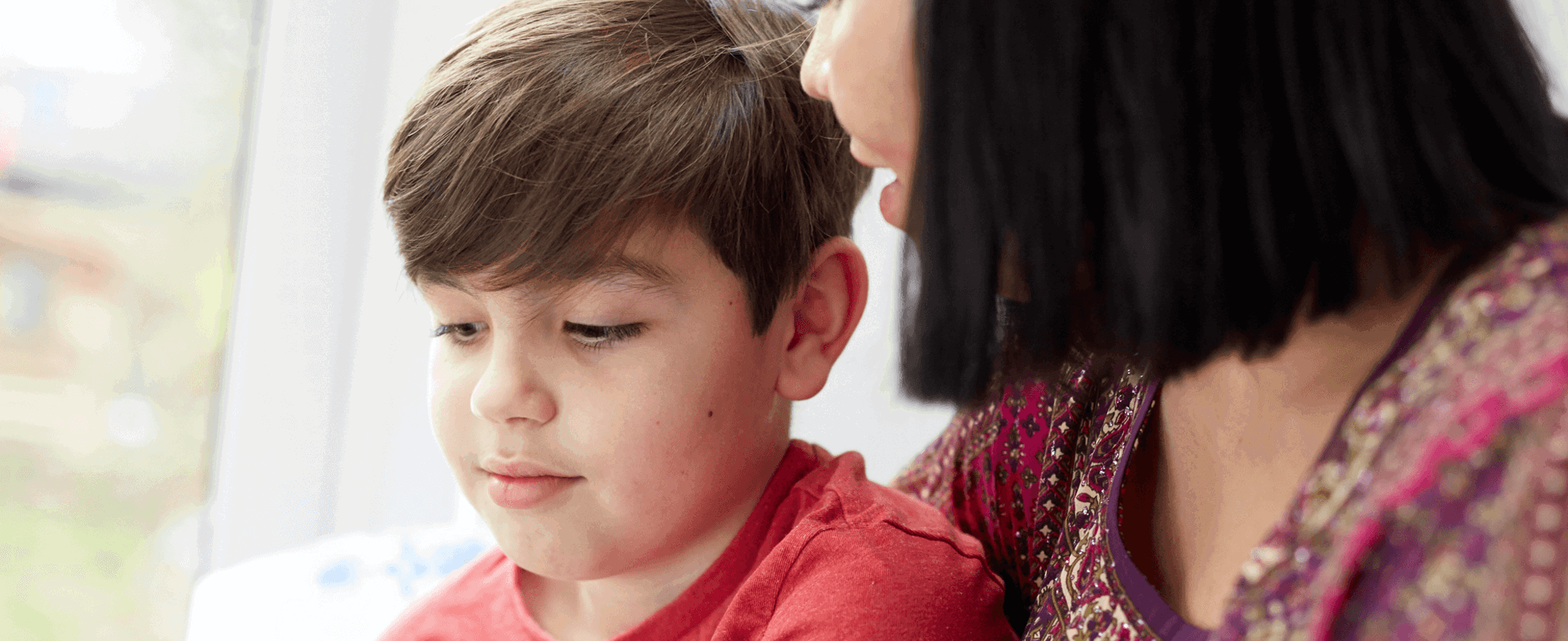 A mother looking at her young son by a window 