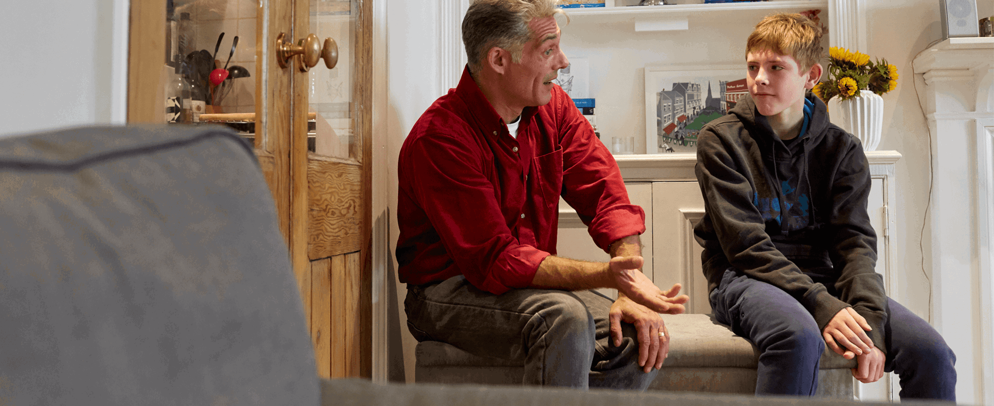 A father and son talking in a lounge seated 