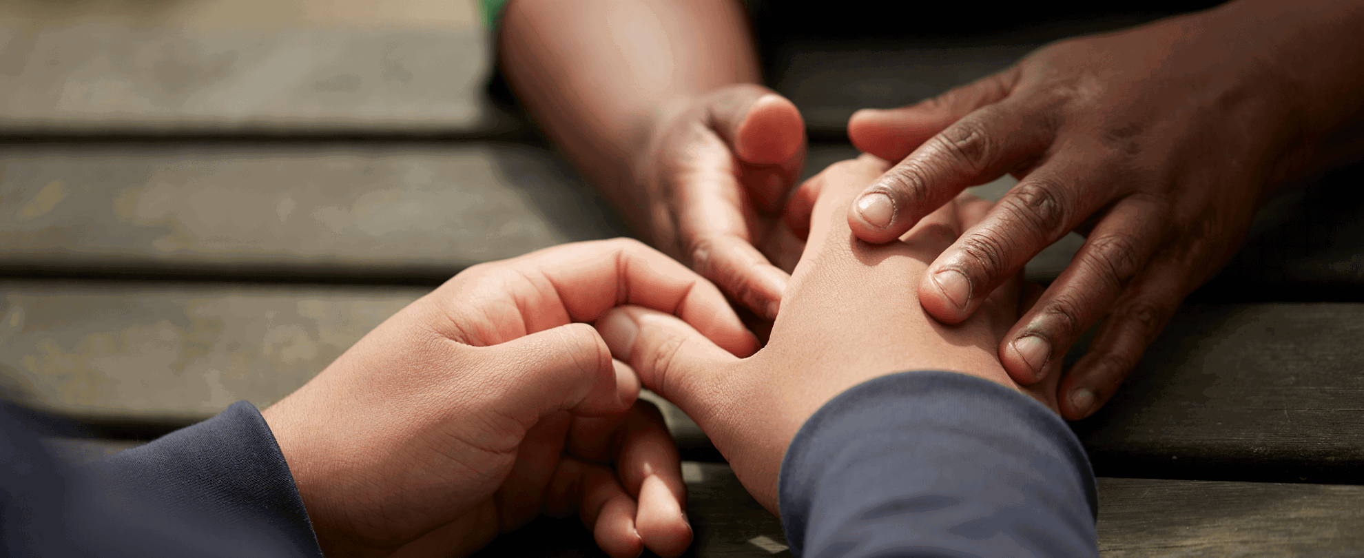Two people holding hands over a table outside 