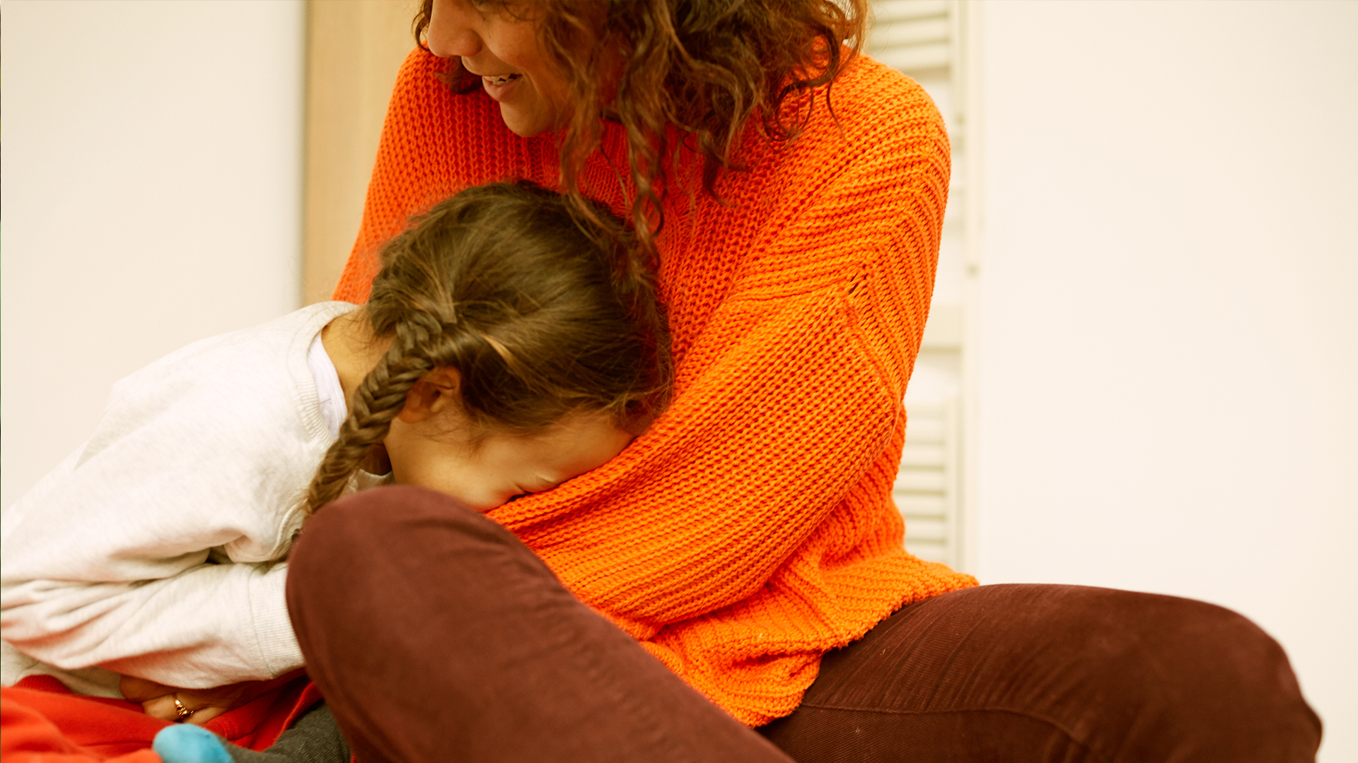 A child laughing with her head in her mum's lap.