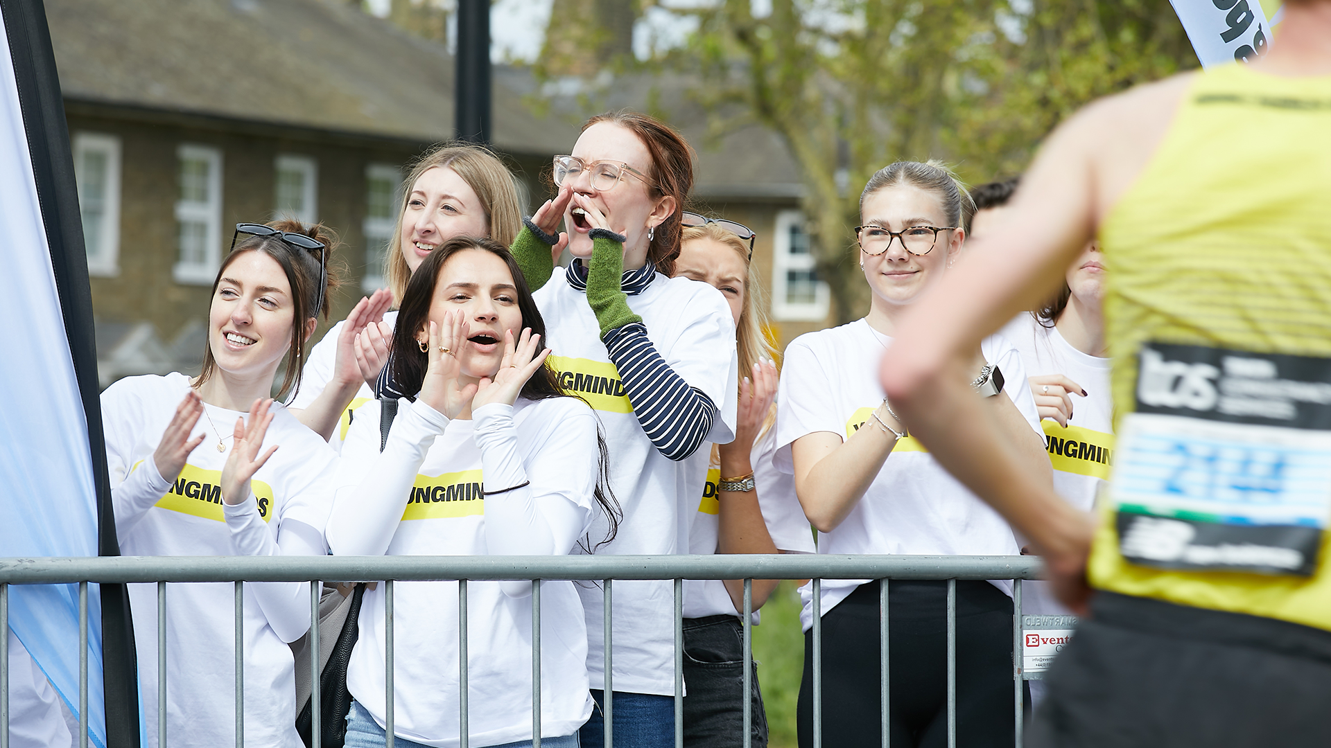 YoungMinds staff cheering marathon runners on from the side line in YoungMinds t-shirts and with YoungMinds banners.